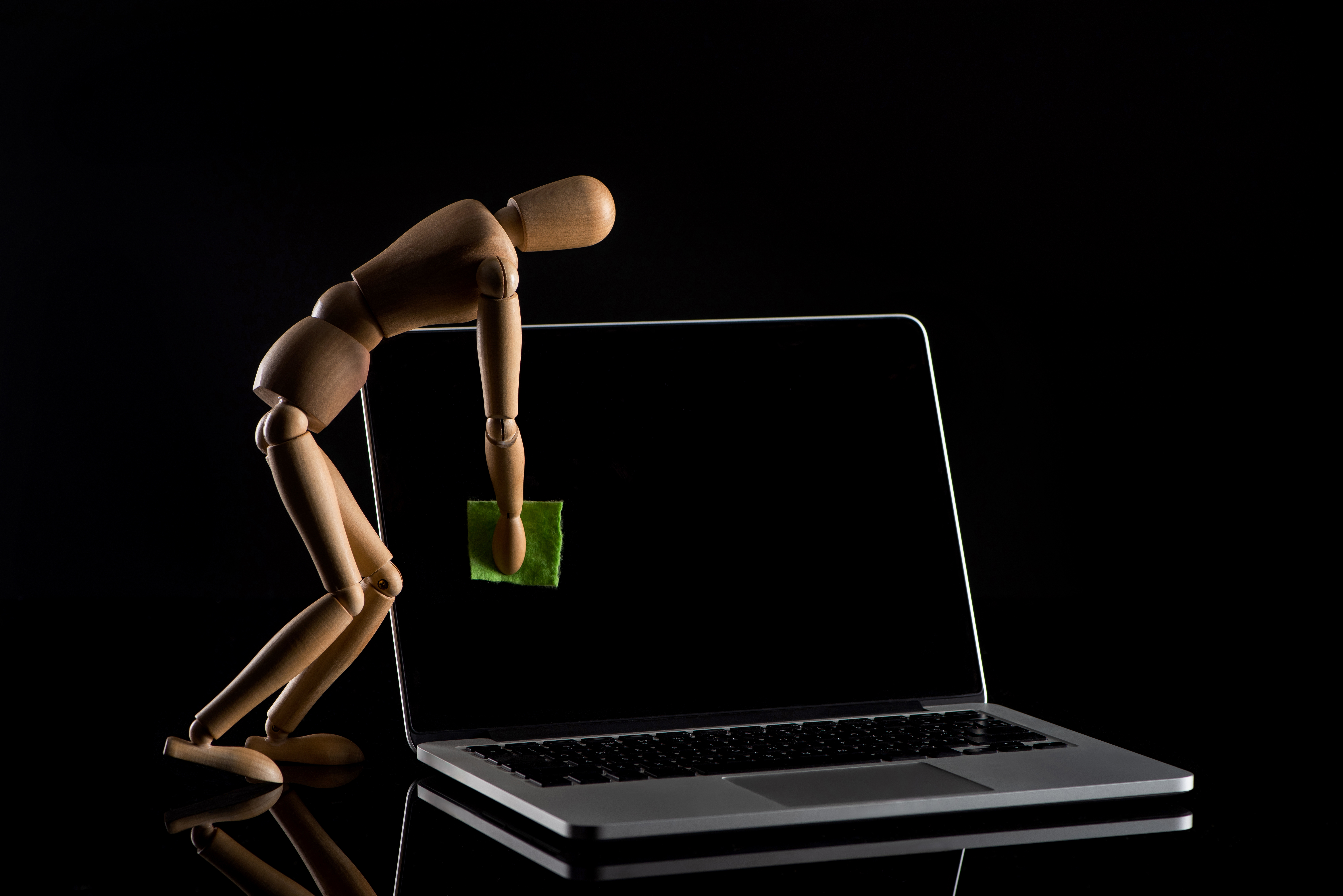 Crello 354064232 stock photo wooden doll imitating dusting laptop