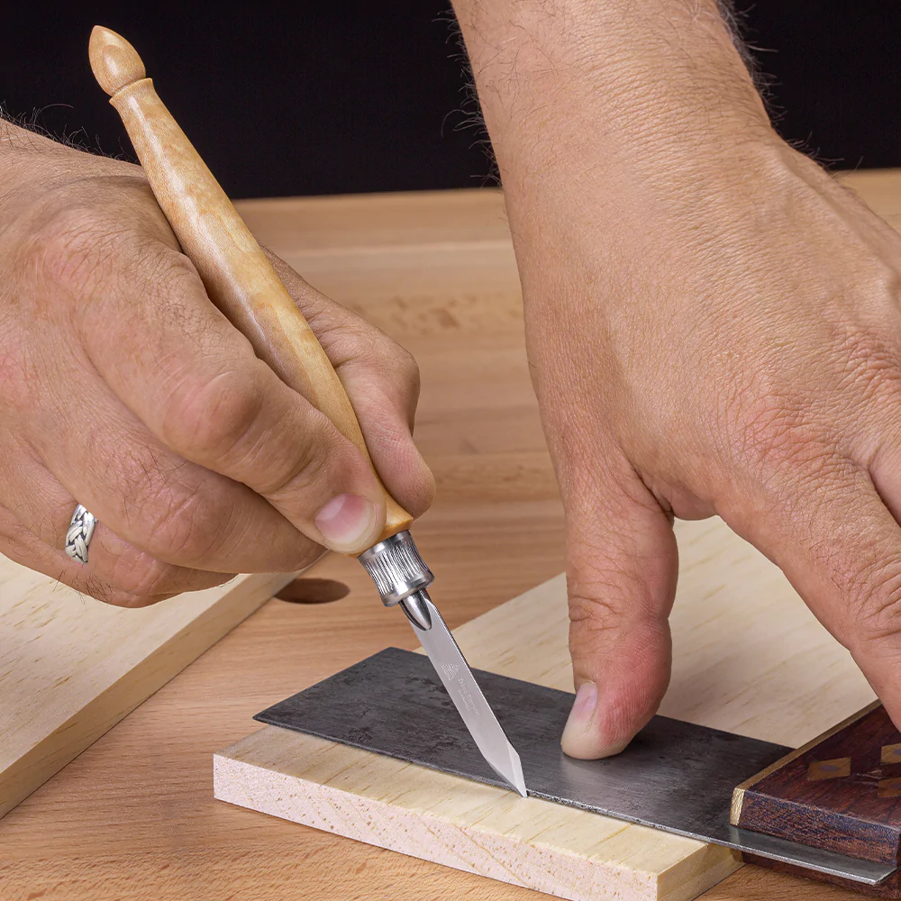 Le couteau de traçage classique Blue-Spruce.
manche en érable madré, lame pointue épaisseur 0.8 mm, virole et peince en acier inoxydable

Ici utilsé avec une équerre ordinaire (non fournie, ici à titre d'illustration).