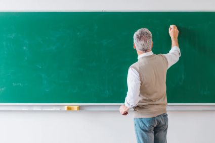 Senior male professor writing blackboard with chalk