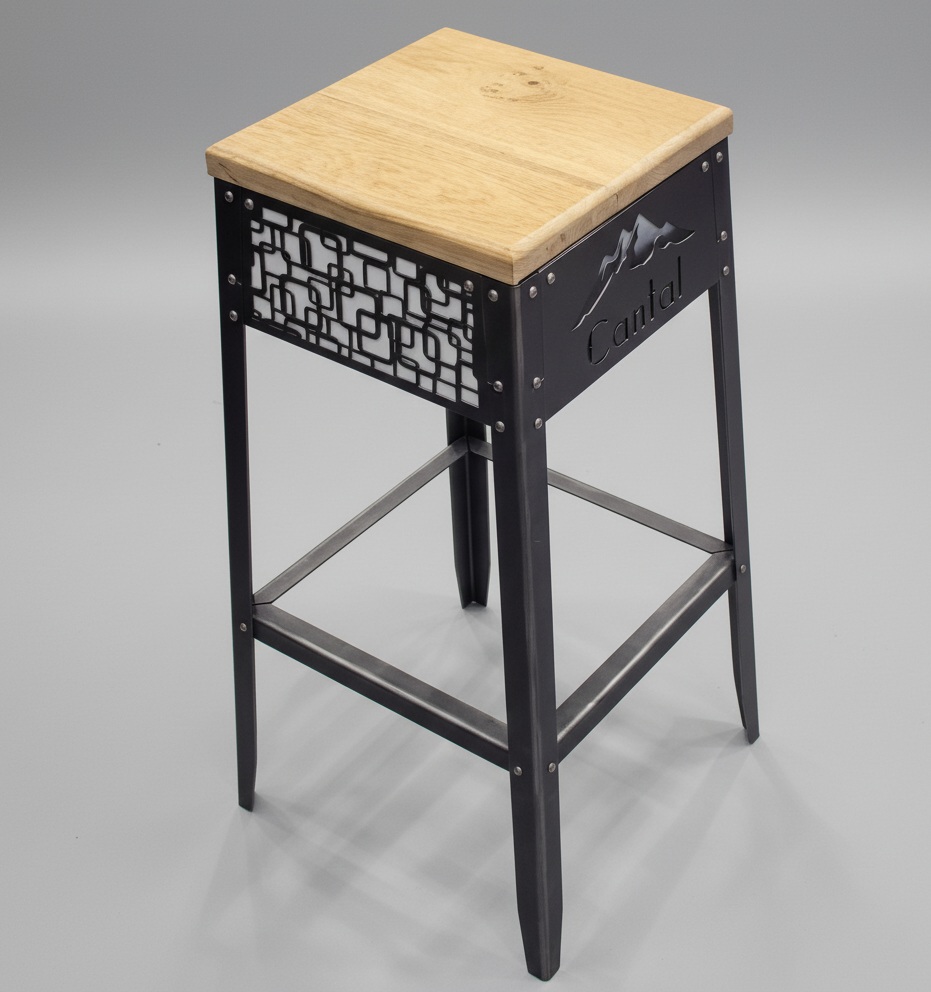 Tabouret de bar de style industriel avec assise en chêne massif et structure en acier personnalisée par découpe laser d'un logo 'Cantal' et d'un motif design.