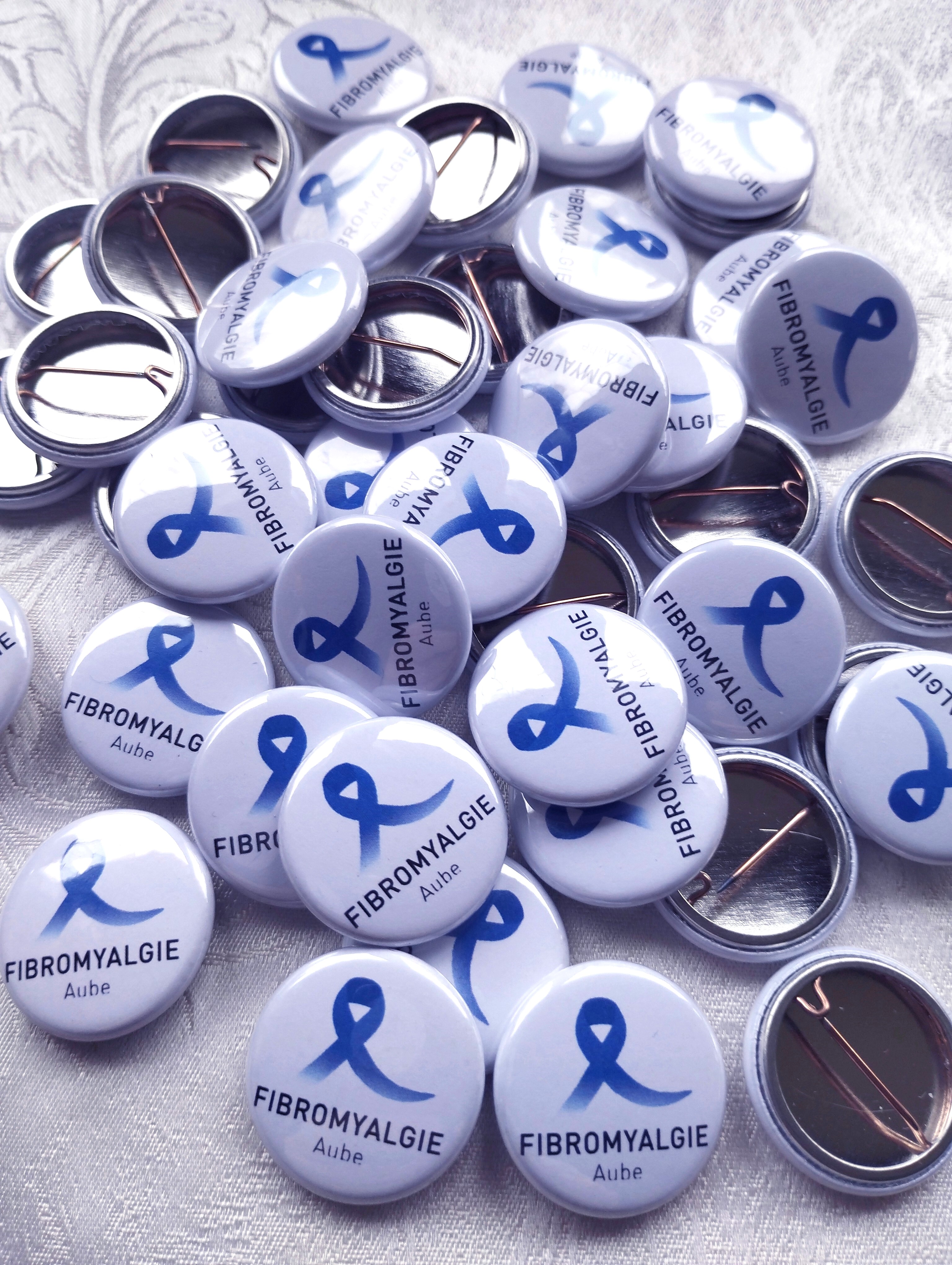 Bagde imprimé à l'effigie de l'association Fibromyalgie Aube, représentant un ruban bleu, symbole de la fibromyalgie.