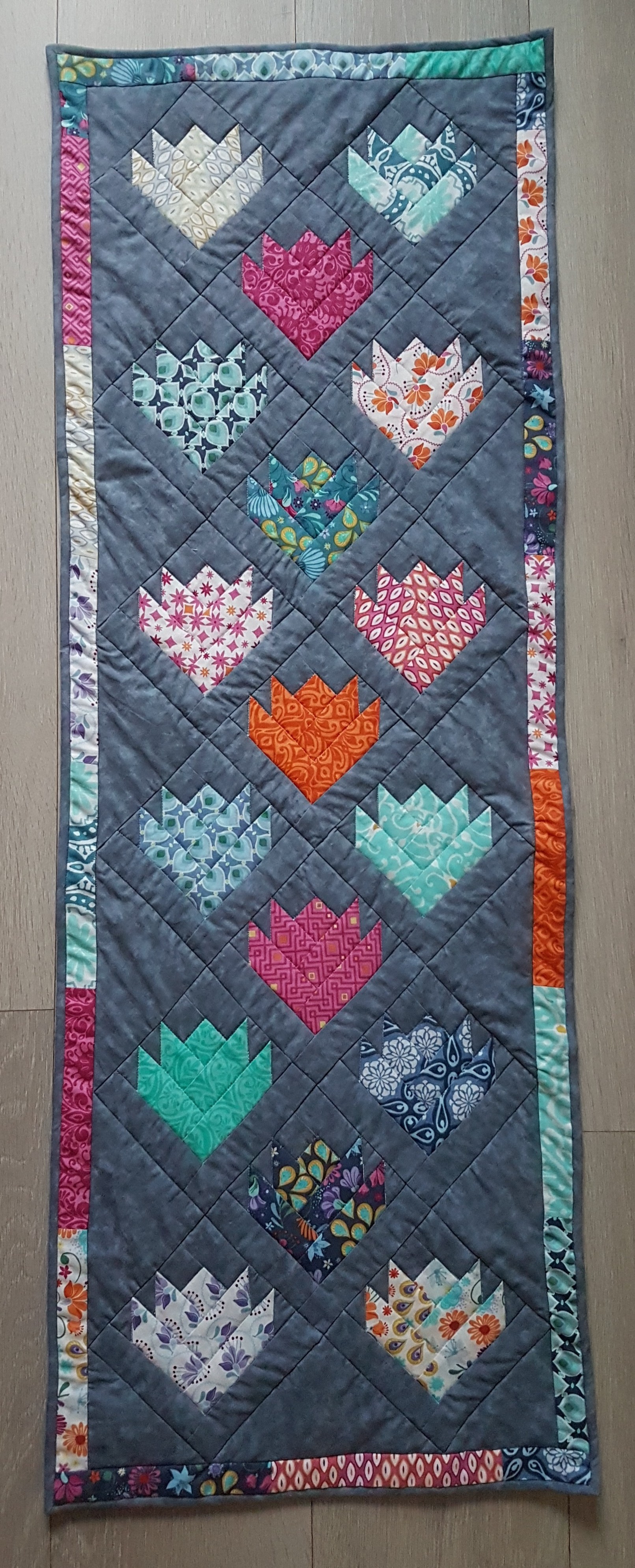 Frühling : S'ensuit l'étape de la mise en place du tissu adossé et du "nuage" qui donne l'épaisseur à l'ensemble. Puis ce sera le Quilting machine qui contribue au rendu final. Enfin, la mise en place du biais au bord de l'ouvrage tout autour, cousu entièrement à la main, assied l'oeuvre dans sa forme définitive : Un chemin de table sur mesure !