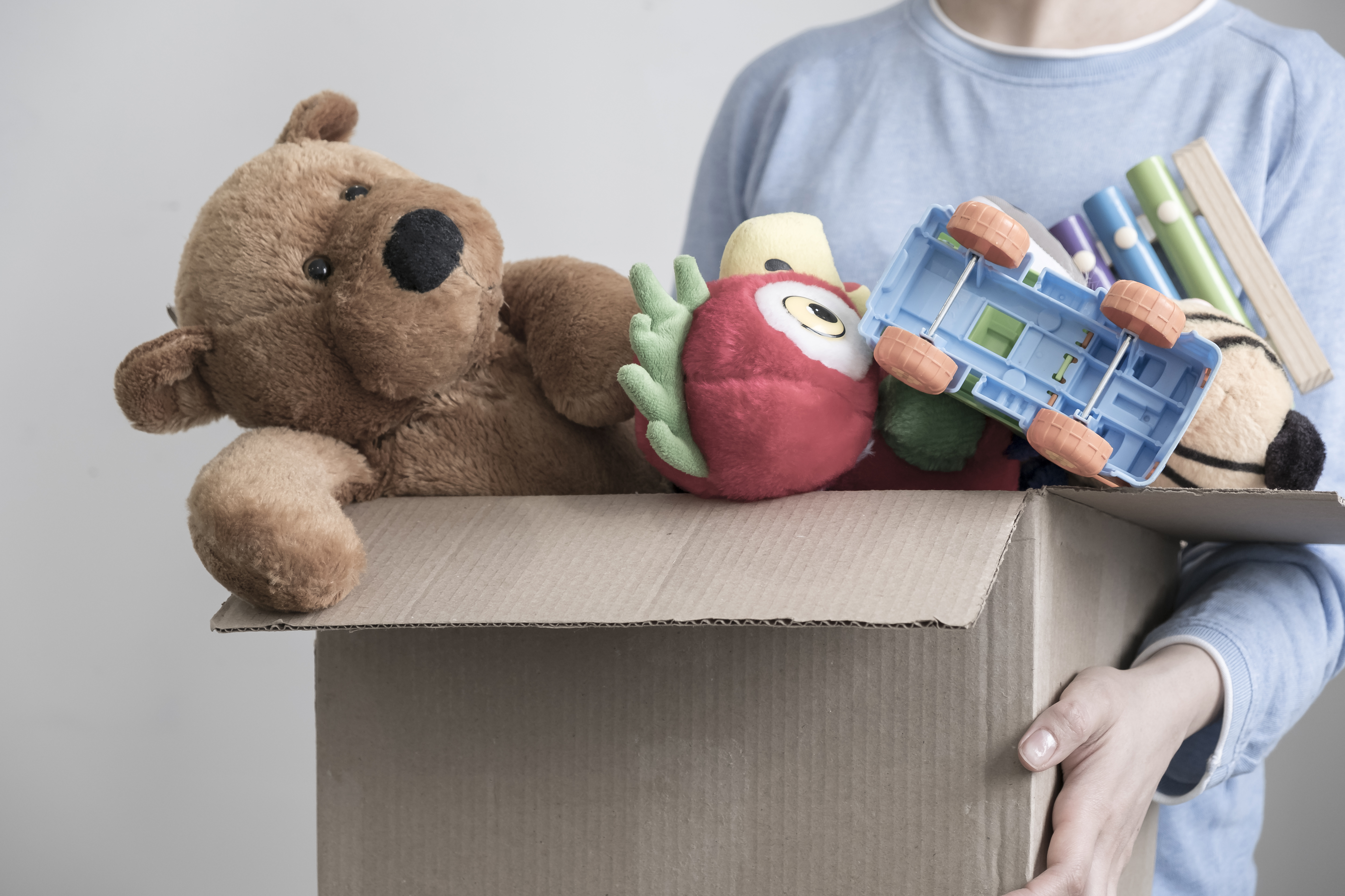 Benevole-masculin-tenant-une-boite-de-dons-avec-de-vieux-jouets