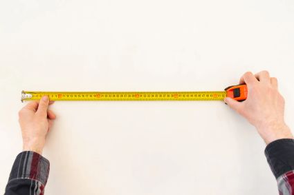 Repairman-builder-measures-length-white-wall-with-tape-measure-closeup