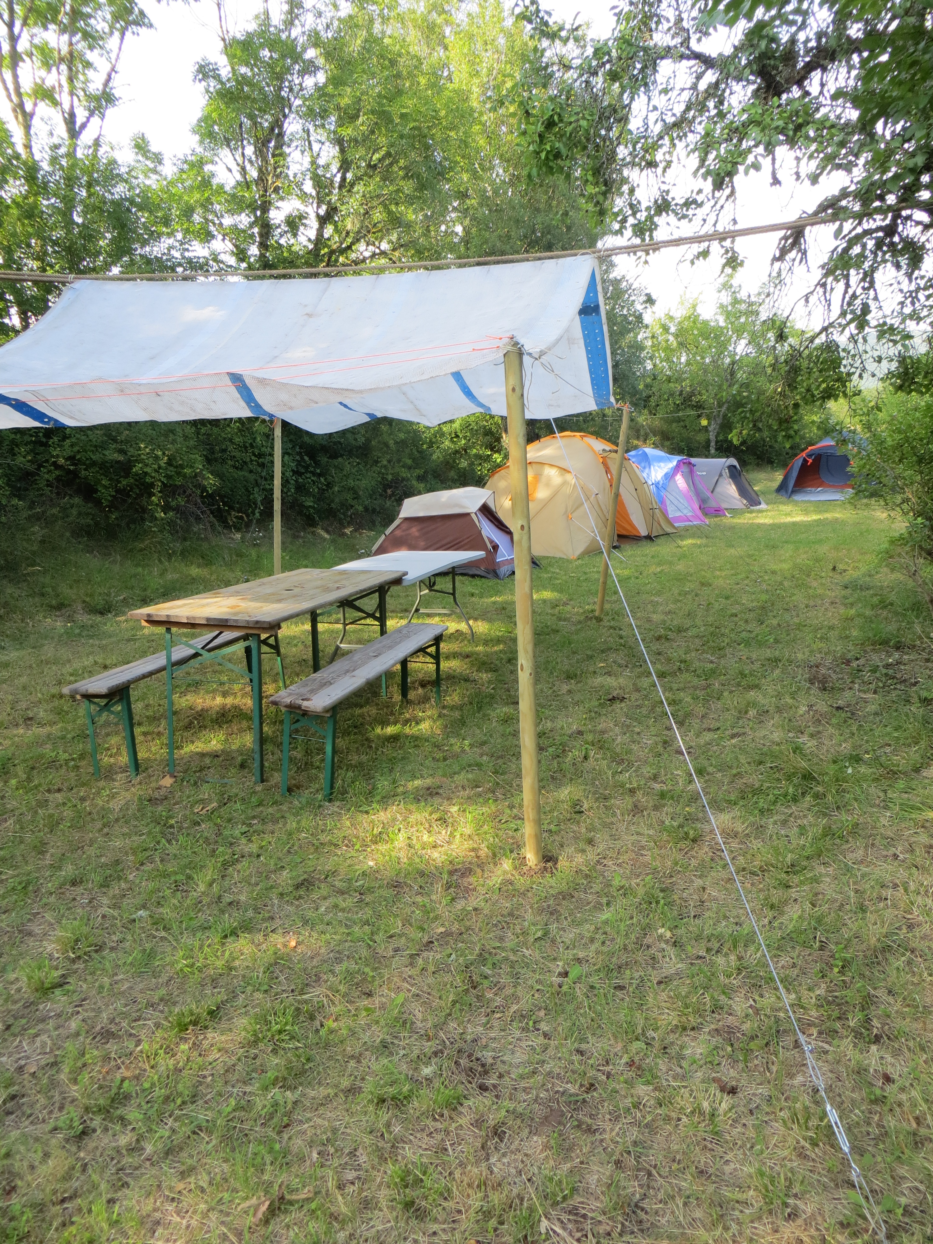 5 tentes à disposition (2 places, 4-6 places, 2 places, 3 places et 3-4 places + matelas), tables et bancs sous abris, fil à linge, .... (barnum plus moderne que sur la photo !)