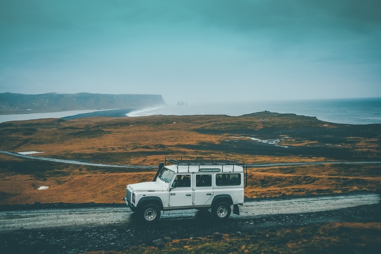Photo-Tout-terrain-blanc-sur-une-route-au-milieu-d-un-paysage-sauvage