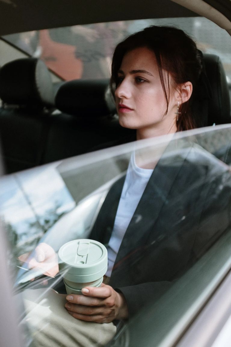 femme tenant un café dans un taxi