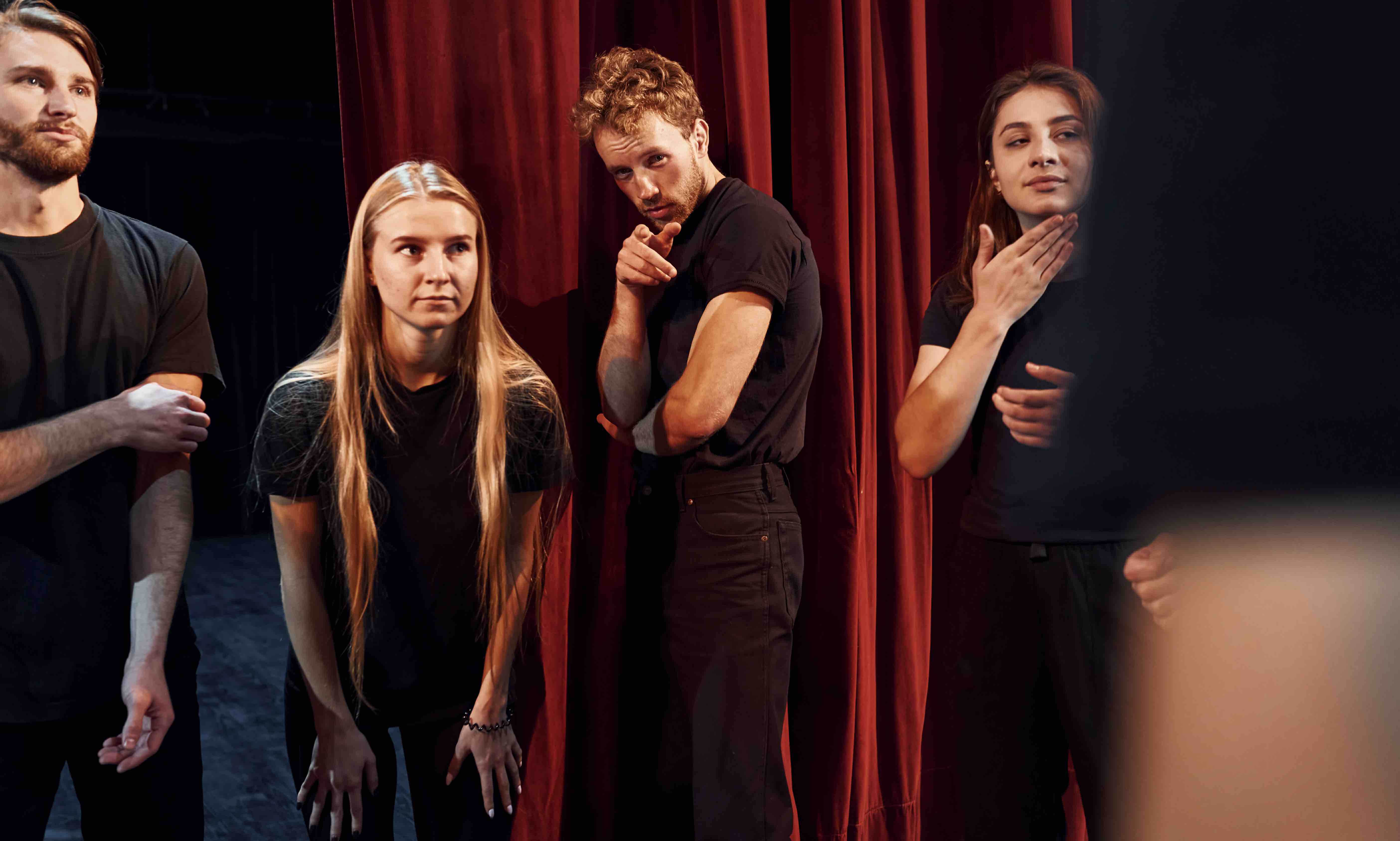 Standing-against-red-curtains-group-actors-dark-colored-clothes-rehearsal-theater