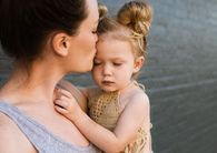 Cette image représente une petite fille dans les bras de sa maman. Une main de la petite fille est posée dans le cou de la maman qui l'embrasse sur le front. Elles ont toutes deux les yeux fermés. Cette image inspire l'amour parent enfant, la tendresse et le partage.