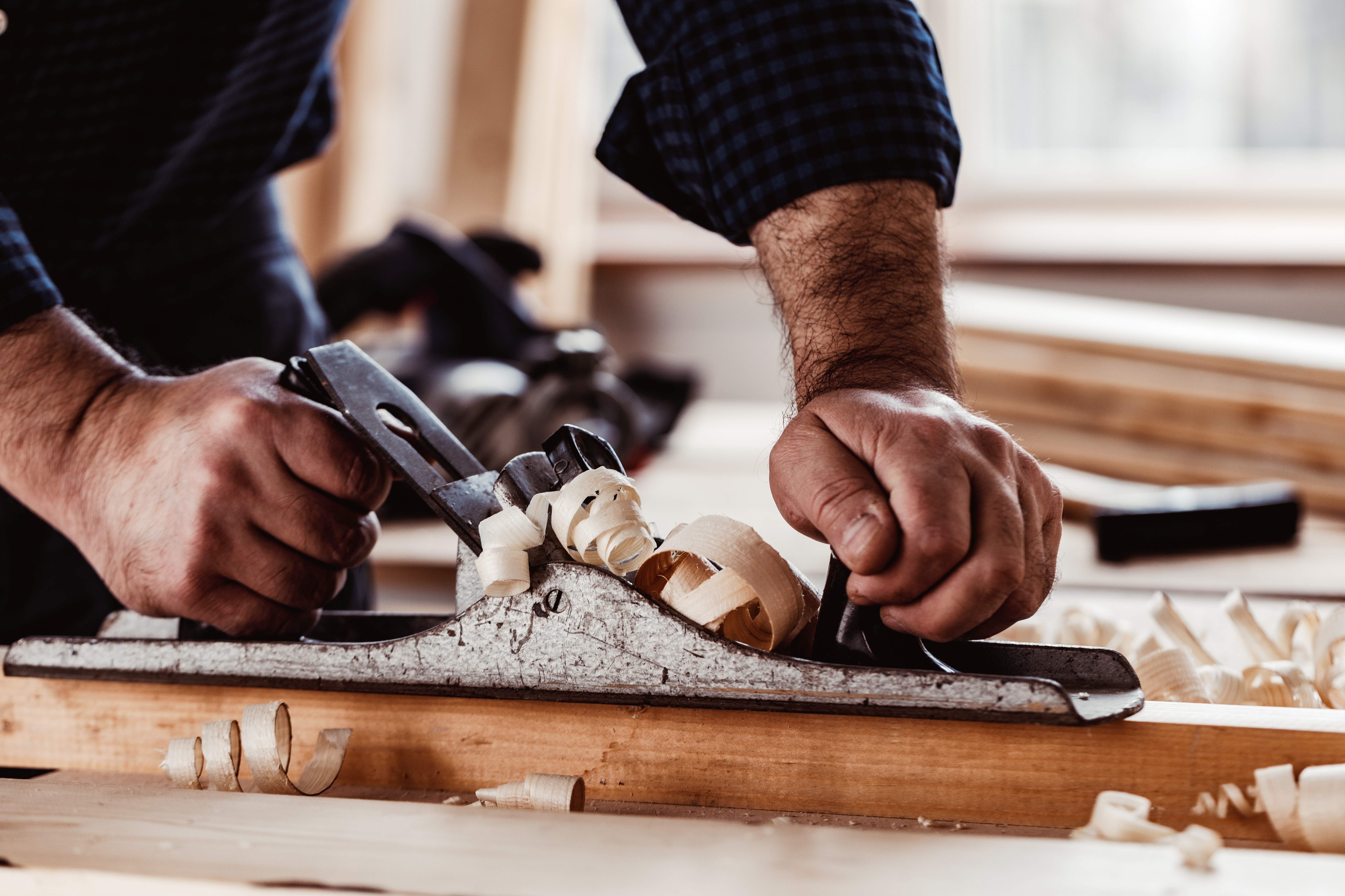 Carpenters-hands-planing-plank-wood-with-hand-plane
