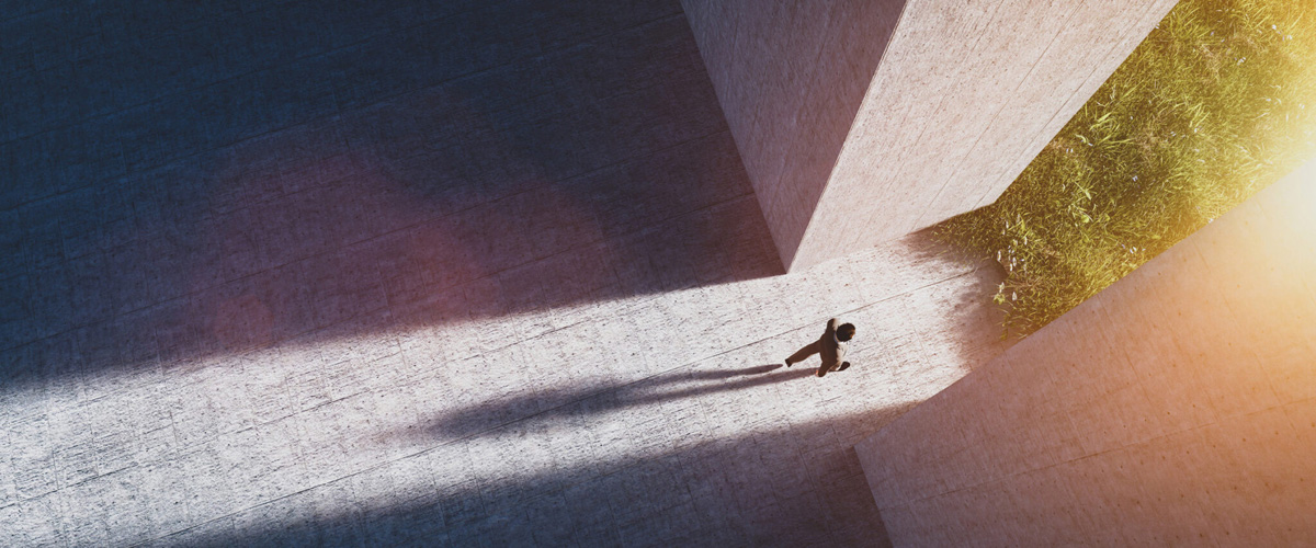 Photo d'un businessman qui sort en marchant d'un grand bâtiment en béton, pour rejoindre la nature.