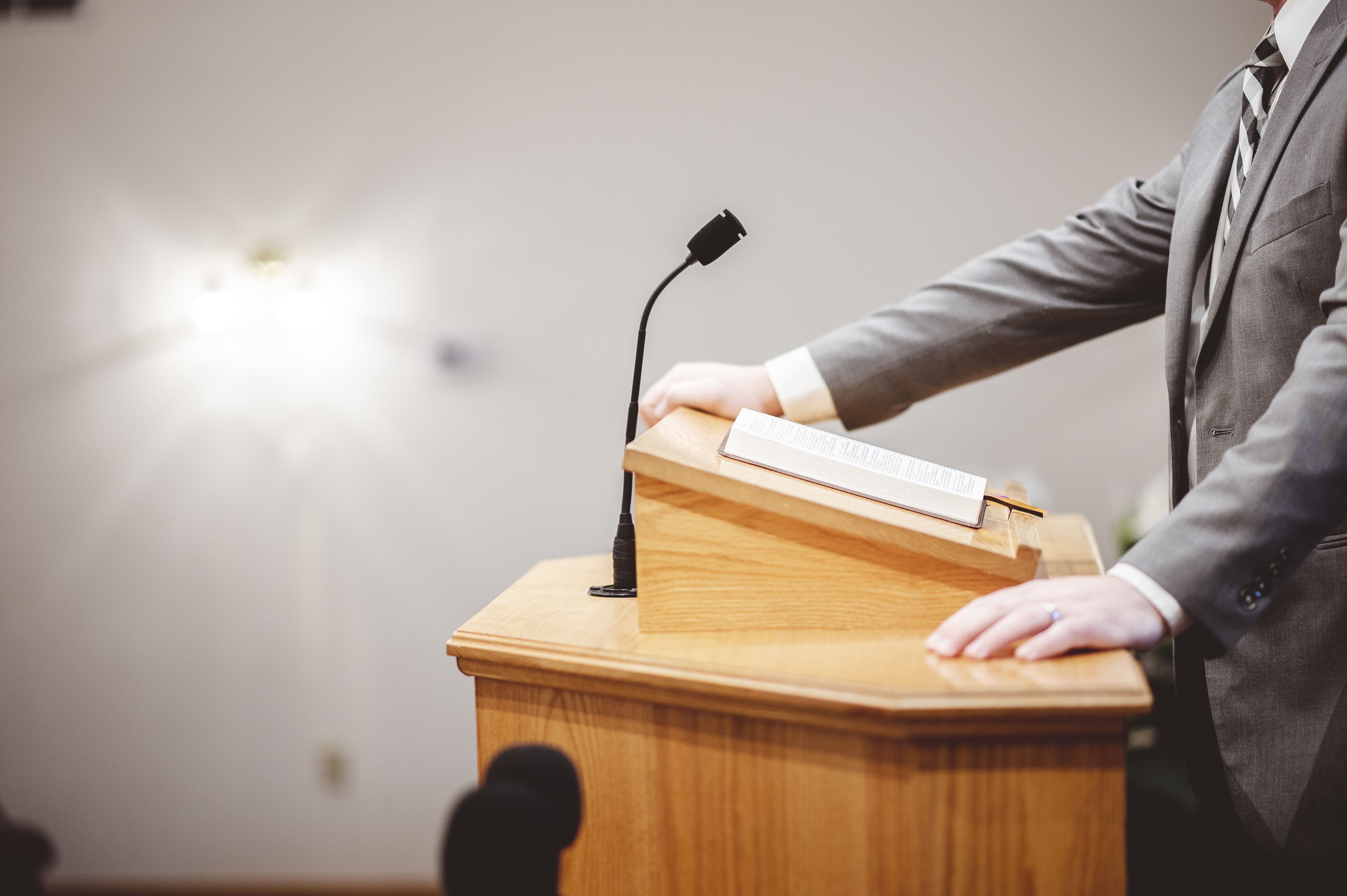 Male formal outfit preaching holy bible from tribune altar church