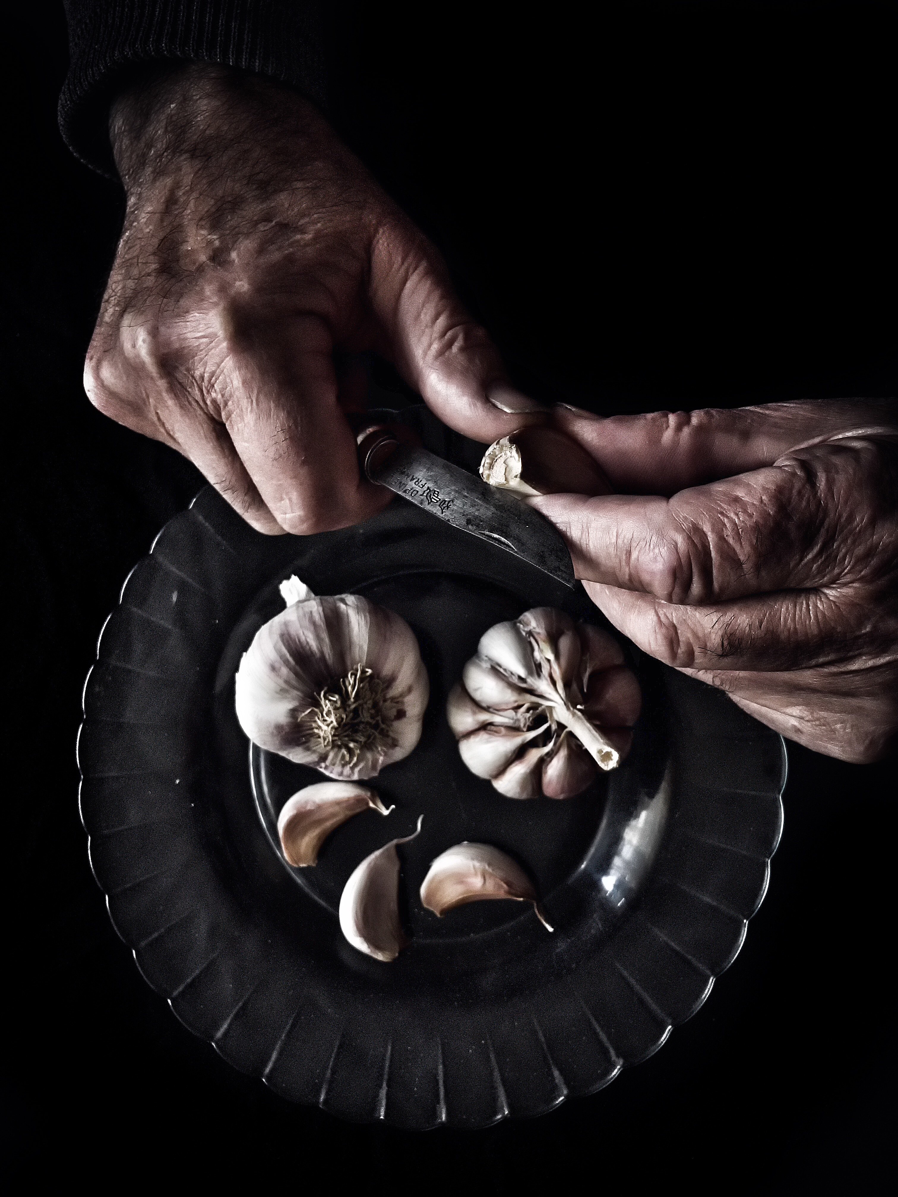 Directly man peeling garlic against black background
