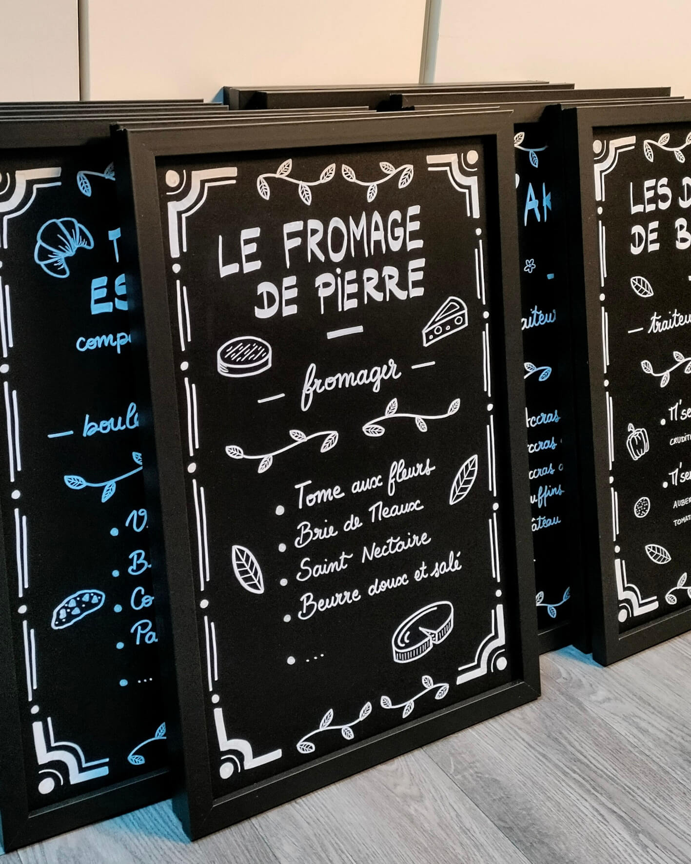 Ardoise décorée pour évènement corporate, un marché de producteurs. Chaque ardoise décorée met en valeur un stand, avec une décoration commune pour une cohérence visuelle et des éléments spécifiques sur-mesure.