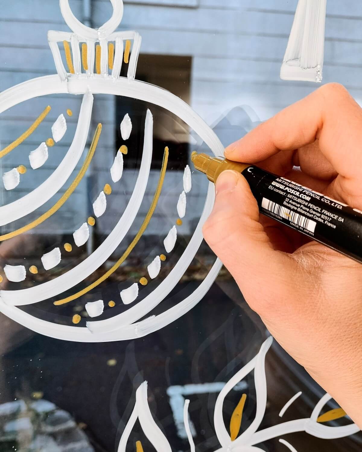 Détail de peinture sur vitrine à la peinture acrylique en blanc et doré