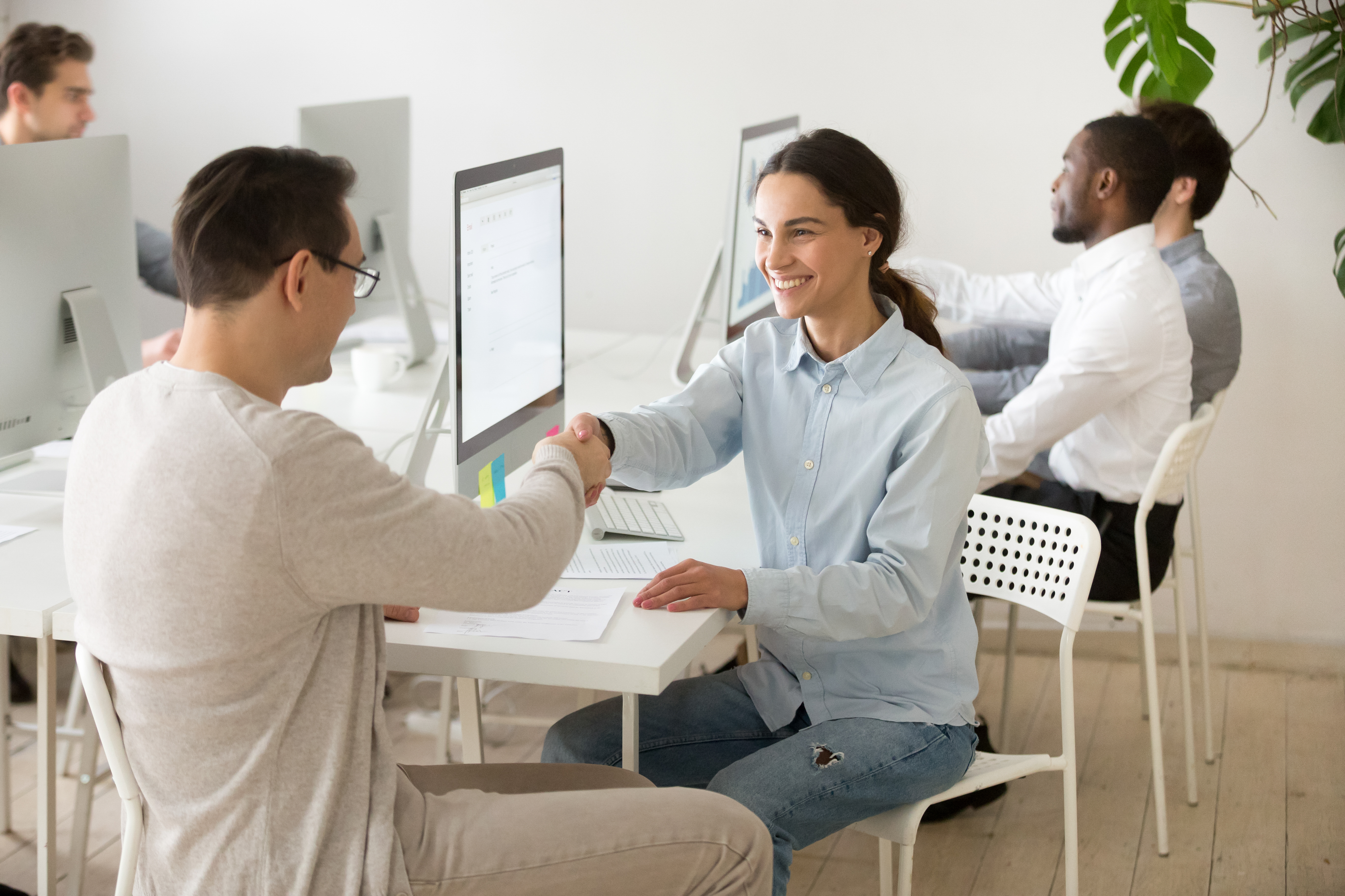 Smiling-young-woman-handshaking-satisfied-client-making-deal-office