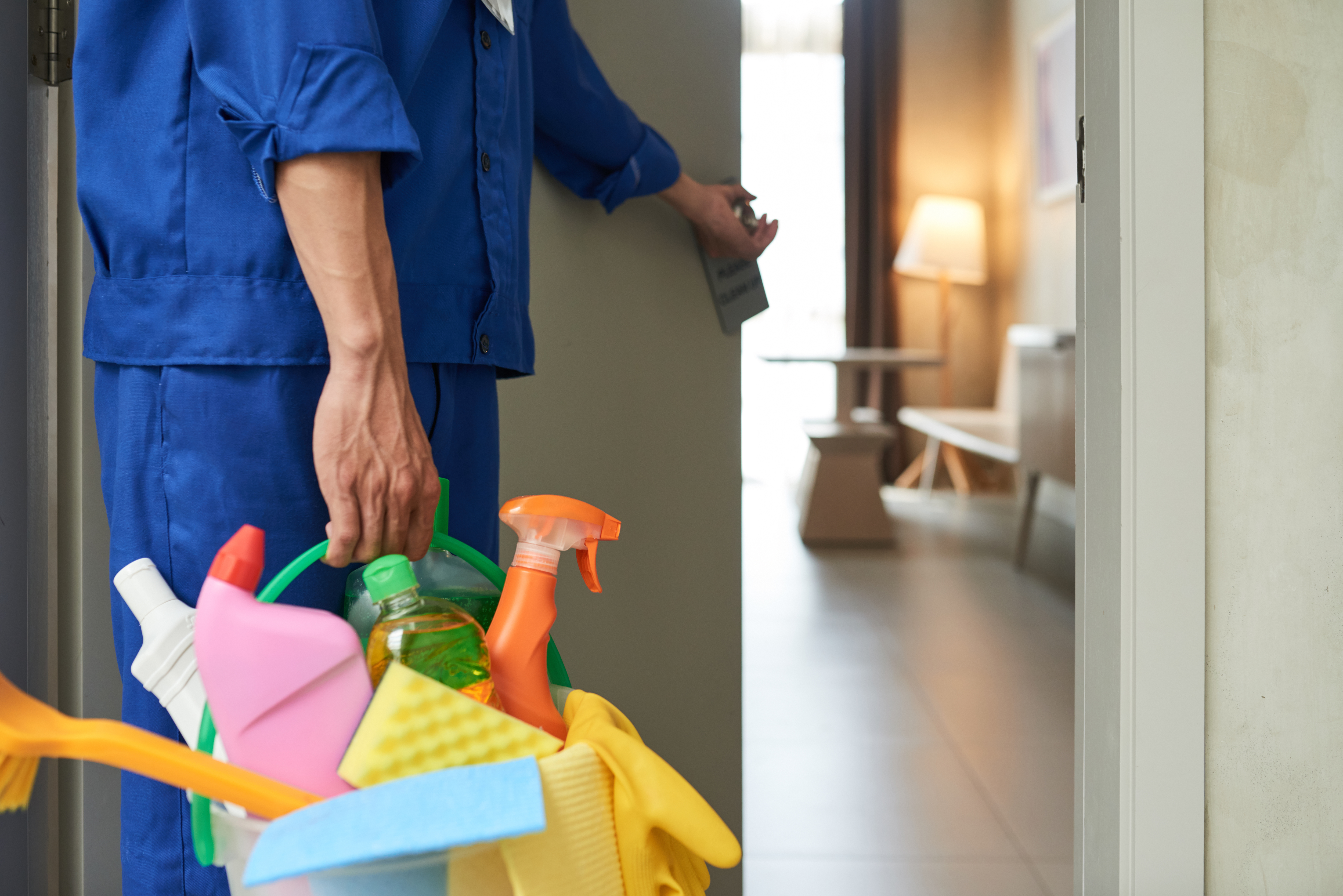 Nettoyeur-non-reconnaissable-qui-entre-dans-une-chambre-d-hotel-avec-des-outils-et-des-detergents