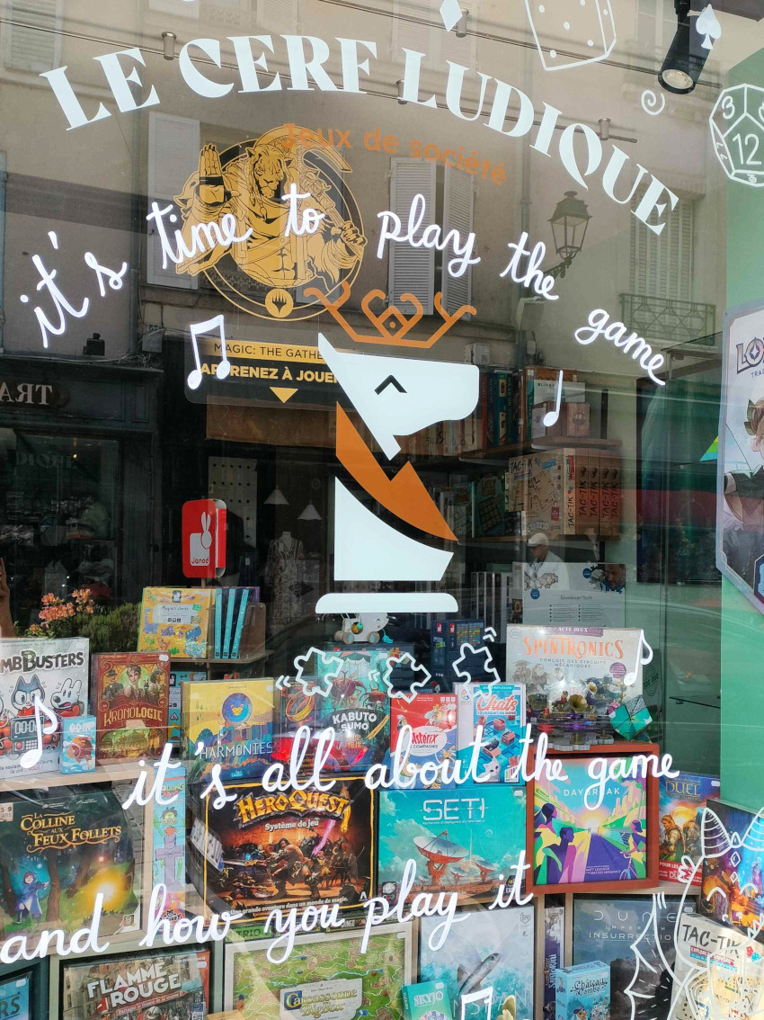 Peinture sur vitrine de paroles de musique chez Le Cerf Ludique, boutique de jeux de sociétés à Rambouillet dans les Yvelines (78)