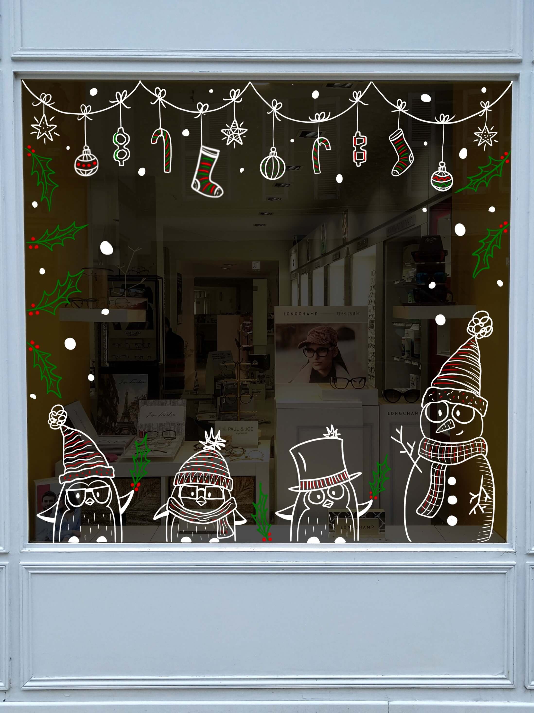 Vitrine de Noël pour un opticien à Rambouillet, avec des pingouins, des bonsommes de neige et des guirlandes par Camille Fauquet