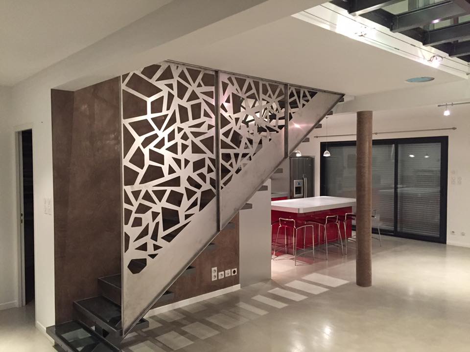 Claustra en métal découpé au laser avec un motif géométrique, servant de garde-corps design pour un escalier dans un intérieur moderne.