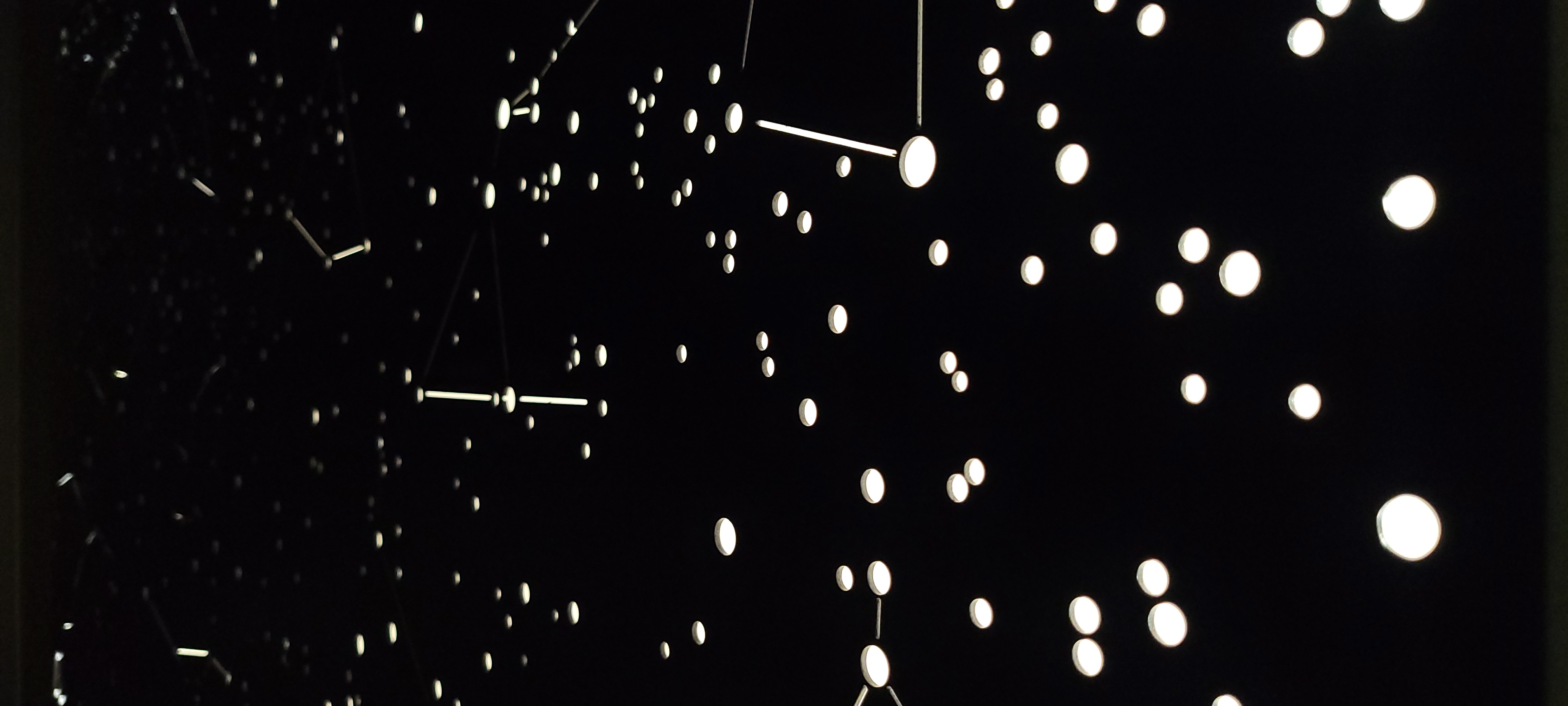 Gros plan sur la tête de lit design 'La tête dans les étoiles', montrant les détails des constellations créées par un éclairage LED intégré et découpes laser.