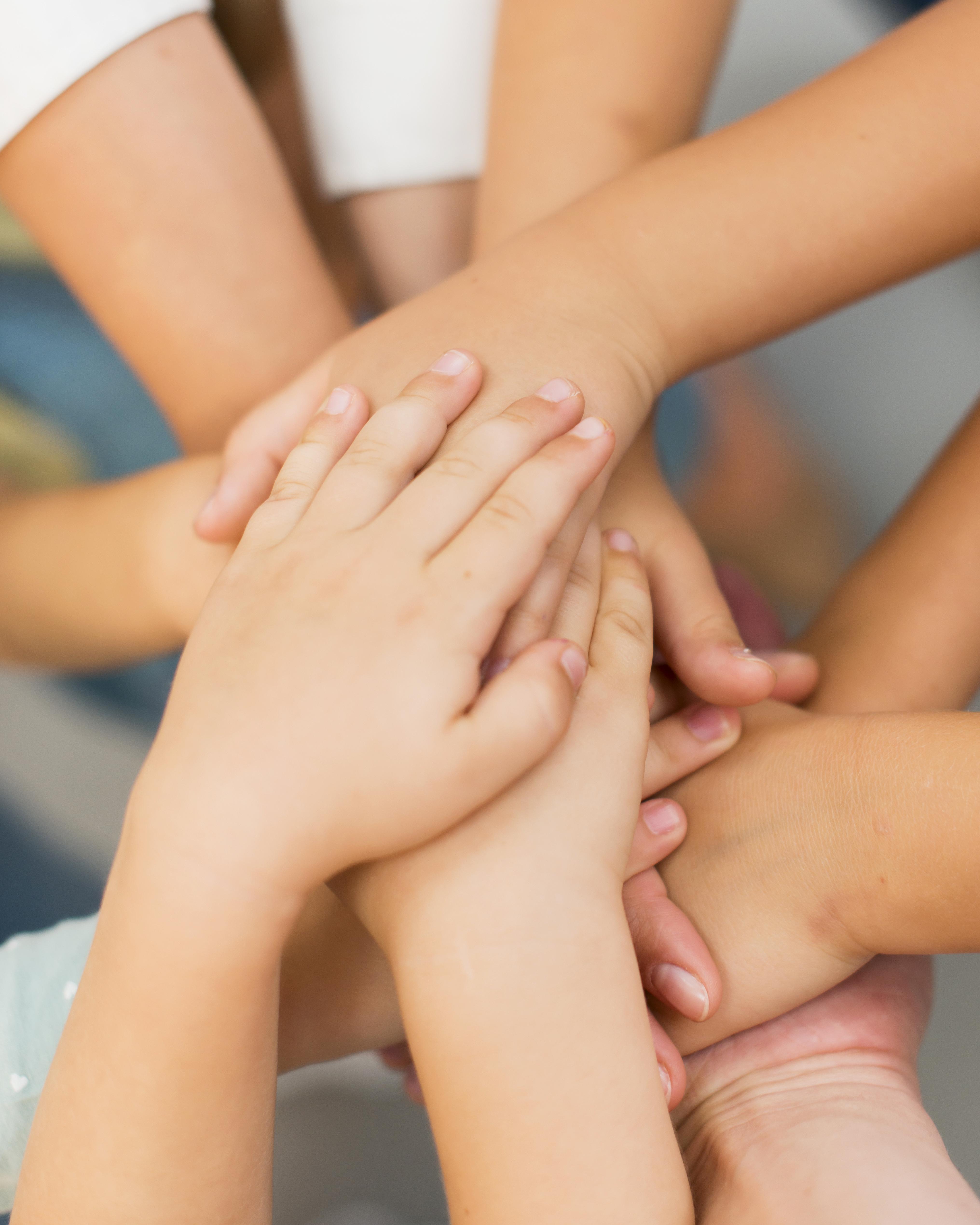 Teacher-putting-her-hands-together-with-her-students-close-up