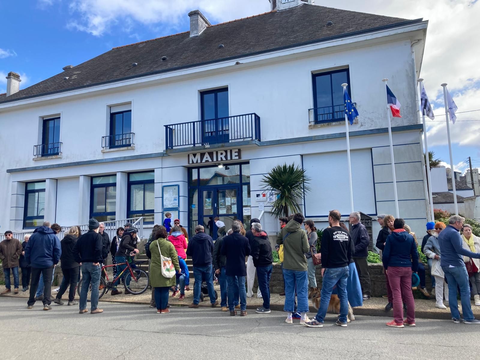 devant le coccimarket, 3 personnes parlent.
