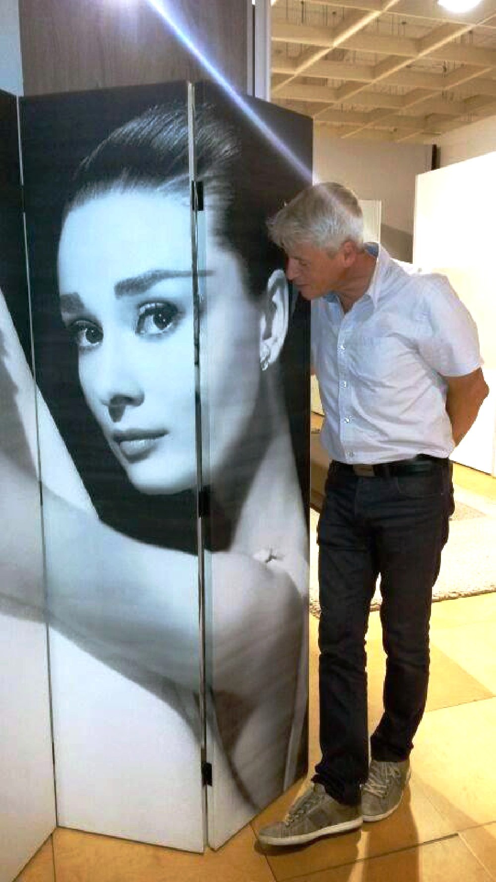 L'artiste David Vereecken contemplant une affiche d'Audrey Hepburn, une source d'inspiration classique au cœur de l'univers Selestica.
