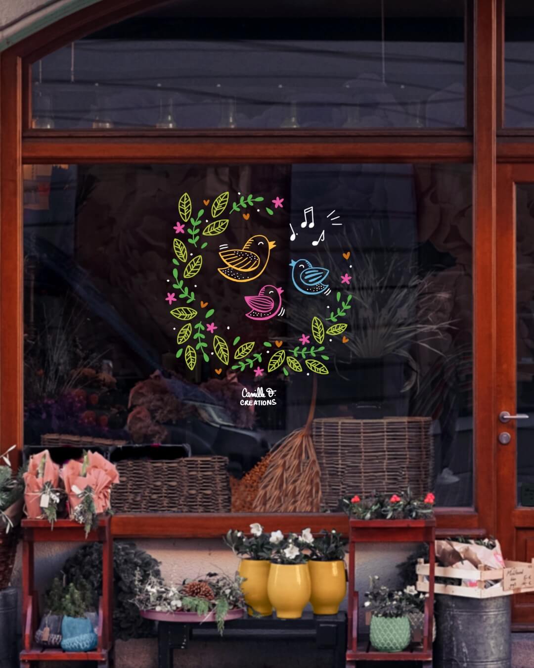 Peinture sur vitrine à Paris ou dans les Yvelines pour le Printemps, représentant une couronne fleurie avec des oiseaux qui chantent
