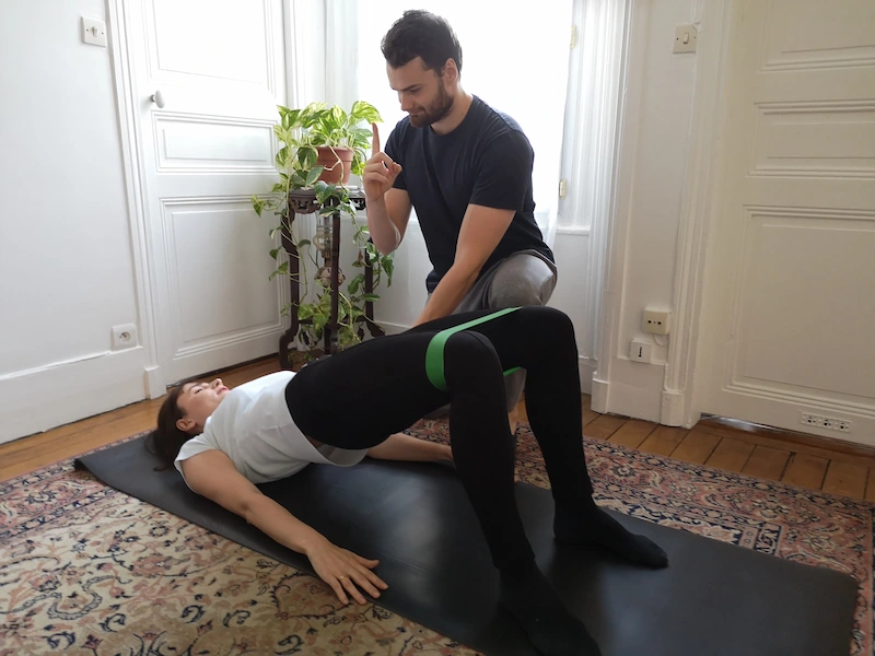 Coach sportif à domicile Paris 6e guidant une cliente sur un exercice de renforcement avec élastique de résistance