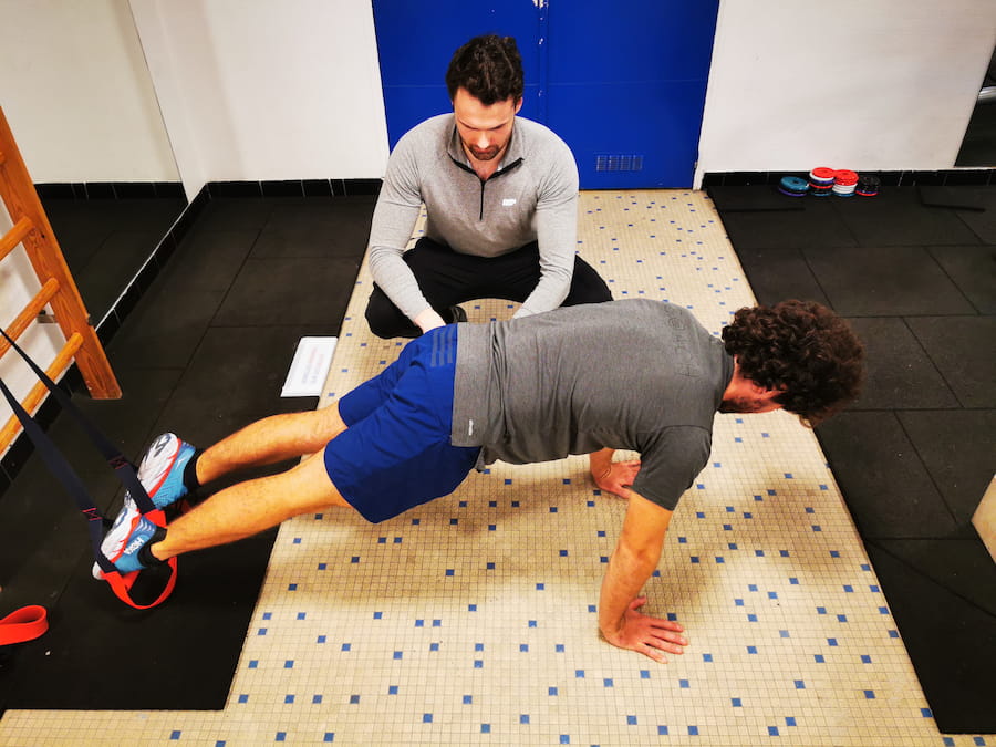 Coach sportif Paris 7 à domicile — supervision d'un exercice de gainage TRX par Alexis Glomeron