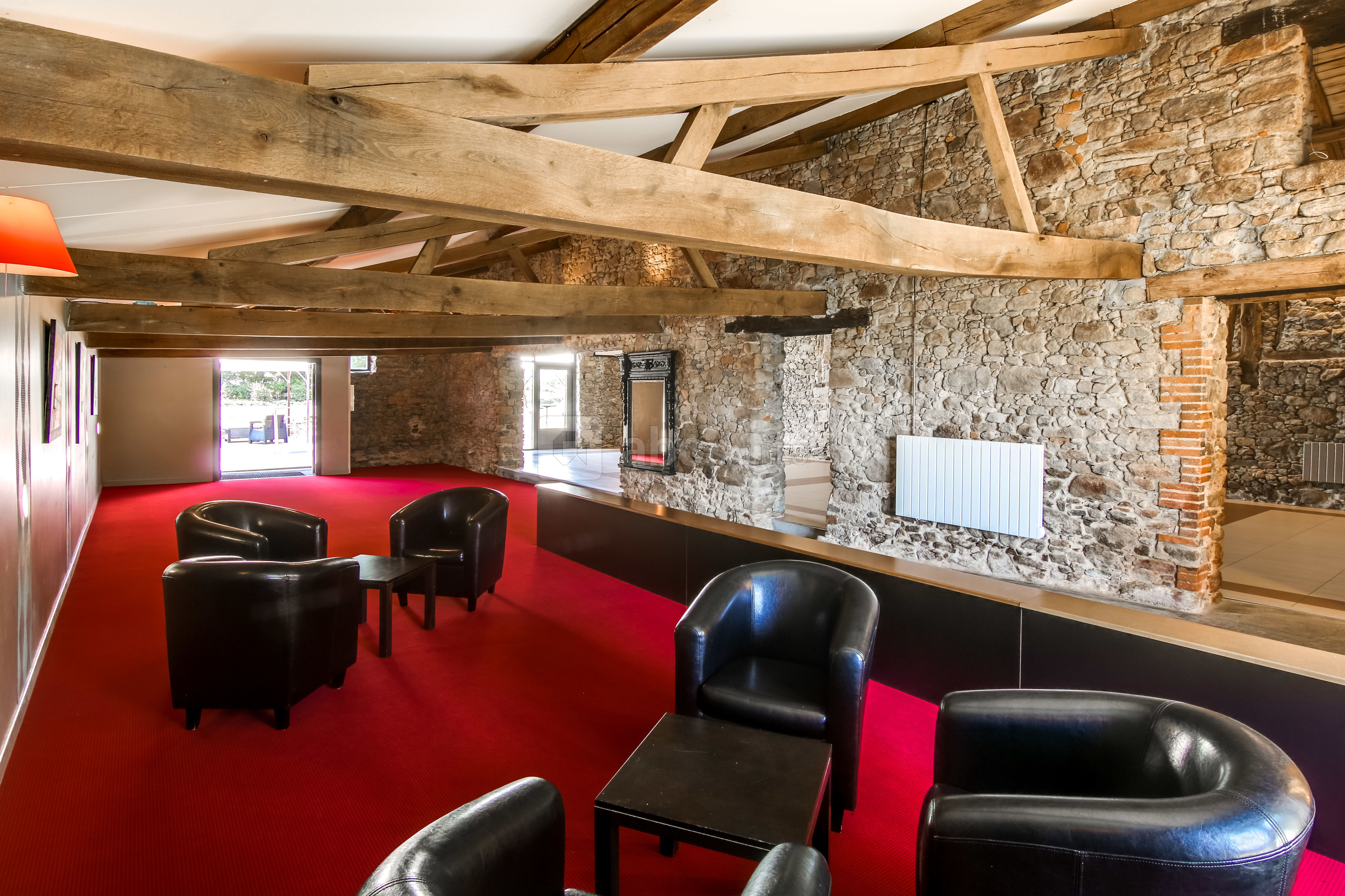 Salon en pierre avec poutres apparentes et fauteuils du domaine