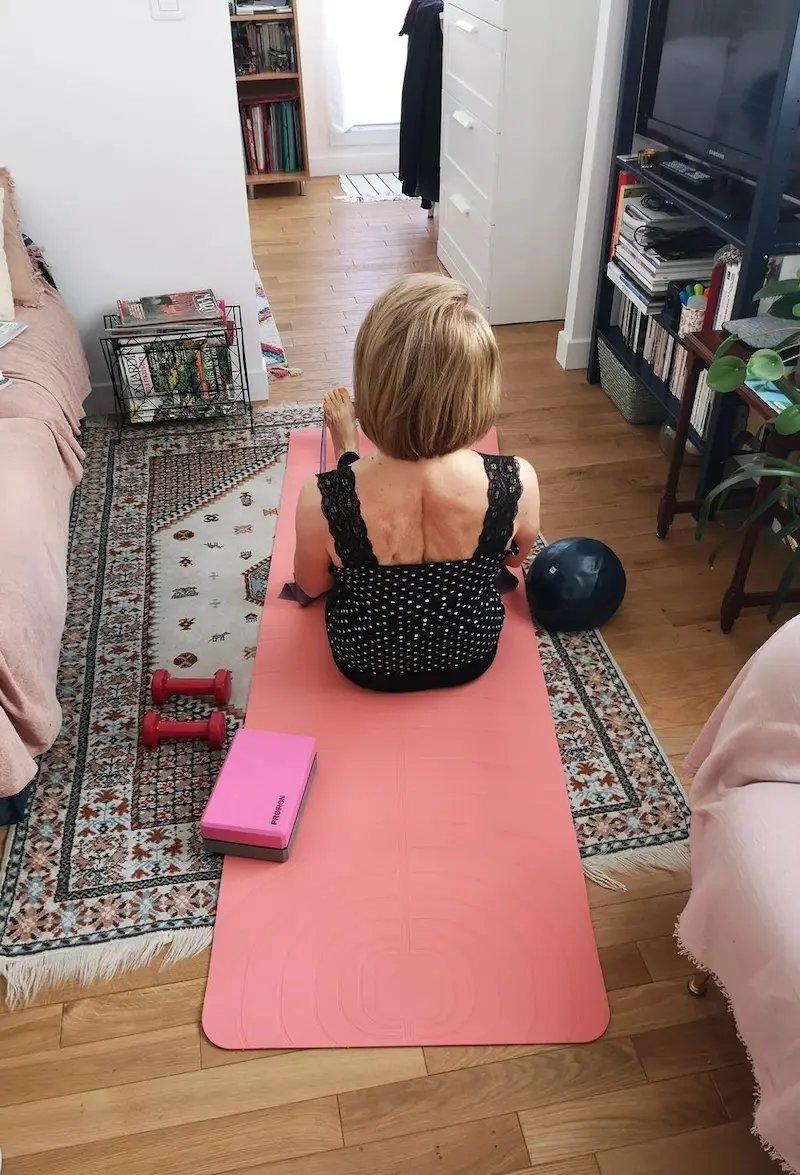 Cliente senior en s&eacute;ance de coaching sportif &agrave; domicile &agrave; Paris avec Alexis Glomeron &mdash; tapis, halt&egrave;res et appartement parisien