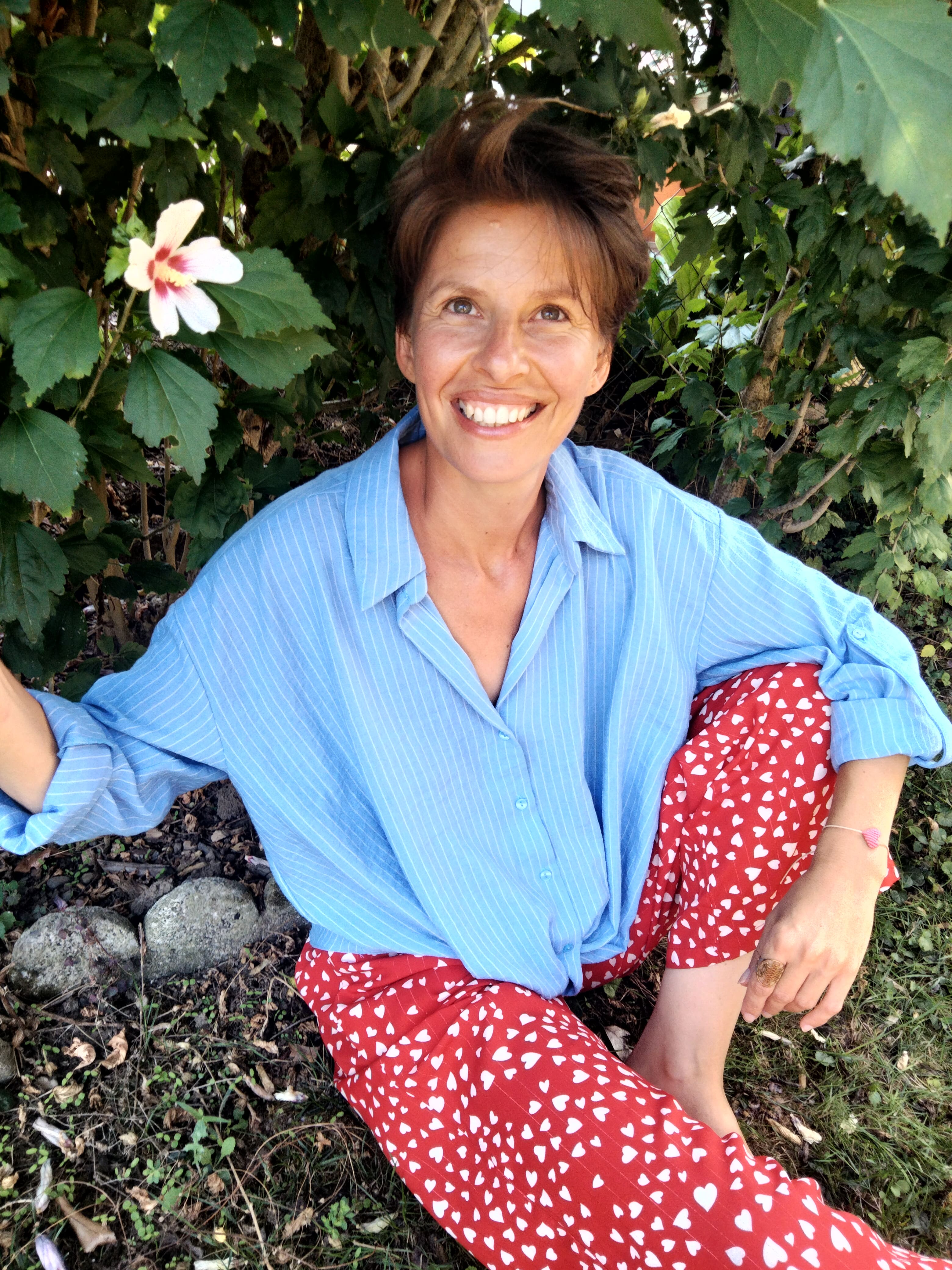 Cette image est une photo portrait de Juliette Cazor, sophrologue enfants, sophrologue adolescents, ambassadrice mon moment magique, animatrice d'ateliers collages. Souriante, des grosses boucles d'oreilles dorées, les cheveux longs attachés à mi hauteur tombant sur l'épaule gauche. 