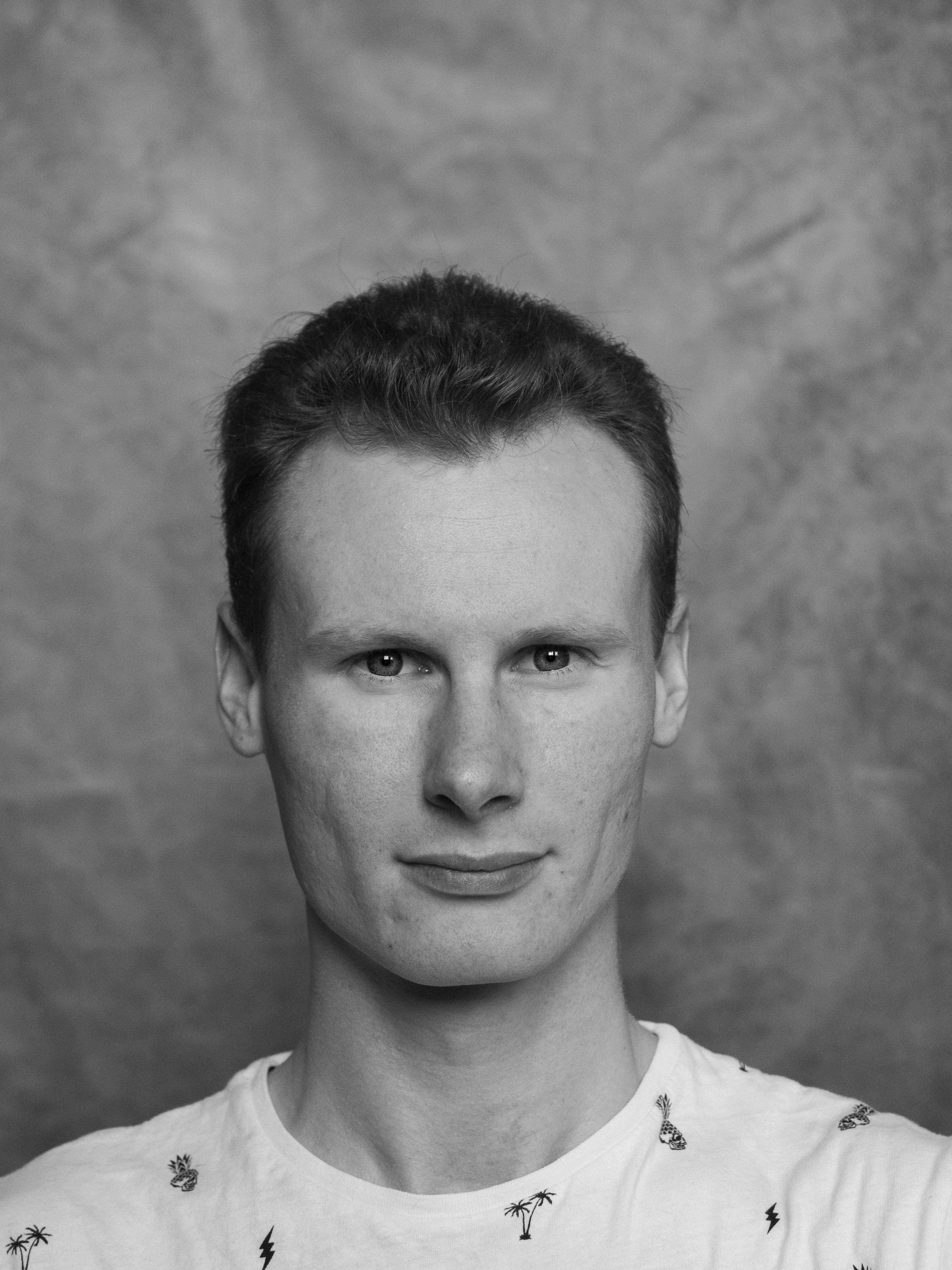 Auto-portrait du photographe professionnel basé à Vernon, capturé en noir et blanc dans un style sobre et accueillant. Cette photo est utilisée pour présenter l'identité du photographe sur son site internet et créer un lien de confiance avec ses clients.