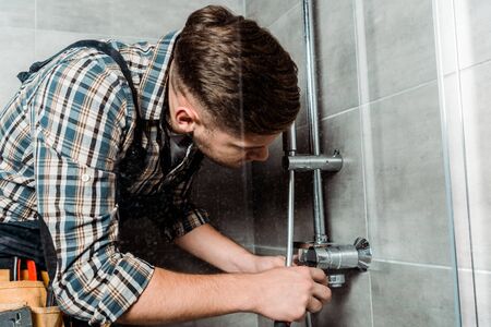 137829558 installateur touchant un tuyau metallique dans la salle de bain 1 